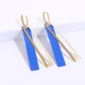 Geometrische blauwe en gouden oorbellen detail, modern lang metaal ontwerp van dichtbij bekeken. - Goud + Koningsblauw