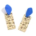 Gedetailleerde close-up van handgemaakte blauwe matte en gouden gehamerde oorbellen. - Goud en Blauw