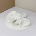 Detailed view of exquisite white bridal feather fascinator hat with delicate floral decor. - White