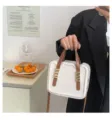 Close-up detail view of the fashionable contrast color biscuit handbag with chic brown handles. - White & Khaki