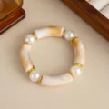 Dettaglio ravvicinato di tubi in resina marmorizzata e perle bianche su bracciale - Bianco avorio