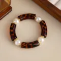Close-up of a tortoiseshell-patterned curved tube bracelet with white faux pearls - Leopard Print
