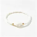 Gros plan sur un bracelet de perles blanches de style bohème avec un accent de coquillage - Conque Blanche