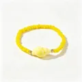 Détail d'un bracelet perles bohème jaune avec un charme de coquillage et billes dorées. - Conque Jaune