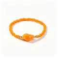 Macro d'un bracelet bohème montrant des perles orange vif et un pendentif de coquillage - Conque Orange