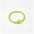 Gros plan sur un bracelet de perles vertes bohème avec un pendentif coquillage brillant - Conque Verte