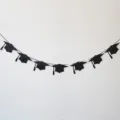 Guirlande de chapeau de remise de diplome noire pailletee fete decoration graduation 2026 - Lot de 7 bannières chapeau de diplômé avec pompons à gauche