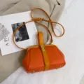 Oranje handtas met litchi-textuur en beugelksluiting, stijlvolle schouder- en crossbodytas. - Oranje