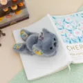 Fluffy grey plush animal keychain with floral accents, cute hanging toy for backpack or keys. - Koala