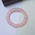 Detailed close-up of a pink transparent telephone cord hair tie with colorful confetti inside. - Coconut Polka Dot Spiral Ring / Pink