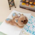 Cute brown lying animal plush toy keychain with floral ears and metal ring, fluffy doll pendant. - Capybara Style