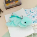 Cute mint green dinosaur plush keychain with floral details, soft toy pendant for bag or keys. - Stegosaurus