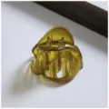 Close-up of translucent amber hair claw clip, showing unique irregular shape and spring detail. - Irregular Shaped Hair Clips / Green