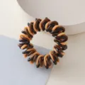 Primo piano dettagliato di un elastico per capelli a spirale intrecciato marrone e beige. - Elastici a spirale marrone, caffè e giallo #4