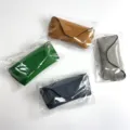 Close up details of portable leather eyeglasses storage case with chain and clear bag packaging. - Gray