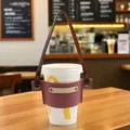 Vista detallada de la funda de cuero para taza con diseño bicolor y correa ajustable. - Rosa