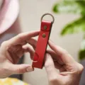 Gedetailleerde close-up van de rode lederen sleutelhanger met fijne stiksels en ring. - Rood