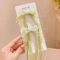 Close-up detail of cute green mesh bow hair clips with long streamers on card display. - Green Long Ribbon Hair Clips - Pack of 2