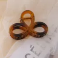 Brown tortoiseshell acrylic hair claw clip with stylish openwork design for daily hair styling. - Amber Figure-8 Hair Clips