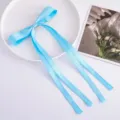 Light blue satin ribbon bow hair clip detail, featuring long streaming tails for elegant hairstyles. - Sky Blue