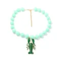 Vue détaillée du collier de perles vert menthe avec un pendentif homard vert unique. - Vert