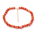 Collana di perle cilindriche arancioni vivaci con catena di estensione dorata donna. - rosso mattone