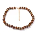 Primo piano della collana di perle marroni effetto tartaruga con catenella dorata. - Marrone scuro