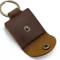 Portable leather guitar pick holder case with metal keyring and snap button closure detail. - Brown