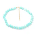 Primo piano della collana di perle azzurre con dettaglio di catena d'oro per lo stile estivo. - Celeste