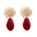 Close-up of woven raffia flower and glossy red acrylic teardrop earrings detail view. - Red