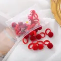 Primo piano di mini elastici per capelli con pon-pon in peluche rosso, carini per bambini. - Serie pompon rosso