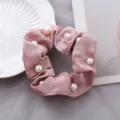 Detailopname van een roze satijnen haarelastiek versierd met elegante parels en sprankelende strass. - Hot-fix strass-steentjes in oudroze