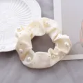 Gedetailleerde close-up van de witte satijnen haarring versierd met glanzende parels en strass. - Beige strass-steentjes