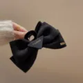 Elegante pinza para el pelo con lazo de terciopelo negro y detalle de placa. - Pinza de lazo triangular negra