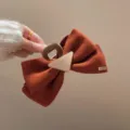 Primer plano detallado del elegante pasador de pelo de terciopelo marrón retro, chic y con estilo. - Pinza de mariposa triangular rojo anaranjado