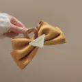 Vista de detalle de la pinza de pelo con lazo de fieltro marrón y detalle de metal. - Pinza de mariposa triangular amarillo jengibre