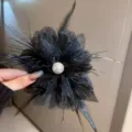 Close-up detail of the elegant black feather mesh flower hair claw clip with a pearl center. - A14 Black