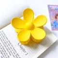 Gedetailleerde close-up van een heldergele bloemhaarclip met een stijlvolle matte textuur. - Gele grote bloem haarklemmen