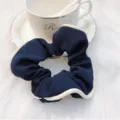 Donkerblauwe stoffen haarelastiek met witte contrastrand, elegante en stijlvolle paardenstaart. - Contrastbies