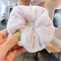 Close-up van een zachte, pluche roze haarscrunchie, met gezellige winterse textuurdetails. - Roze