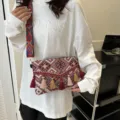 Detail view of ethnic woven crossbody bag with colorful tassels and geometric patterns. - Red