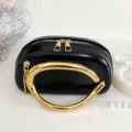 Black fashion handbag with unique gold metal handle and zipper detail close up view - Black