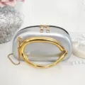 Detail view of the silver metallic handbag featuring a large bold gold circular handle. - Silver