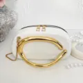 Elegant white structured crossbody bag featuring a statement gold-tone metal handle and chain. - White