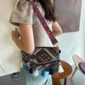 Ethnic style woven crossbody bag detail, featuring colorful geometric patterns and playful tassels. - Black