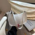 White patent leather shoulder underarm bag detail closeup showcasing smooth glossy texture and hardware. - White