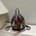 Detailed view of bohemian style woven mini backpack with colorful tassels and geometric straps. - Blue