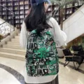 Detailed view of the stylish graffiti casual backpack with cool letter and dinosaur prints. - Green