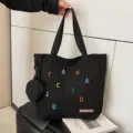 Black canvas tote bag with a small coin purse and colorful embroidered letters for daily casual use. - Black