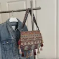Ethnic style woven shoulder bag with intricate geometric patterns, tassels, and wide strap. - Dark Brown